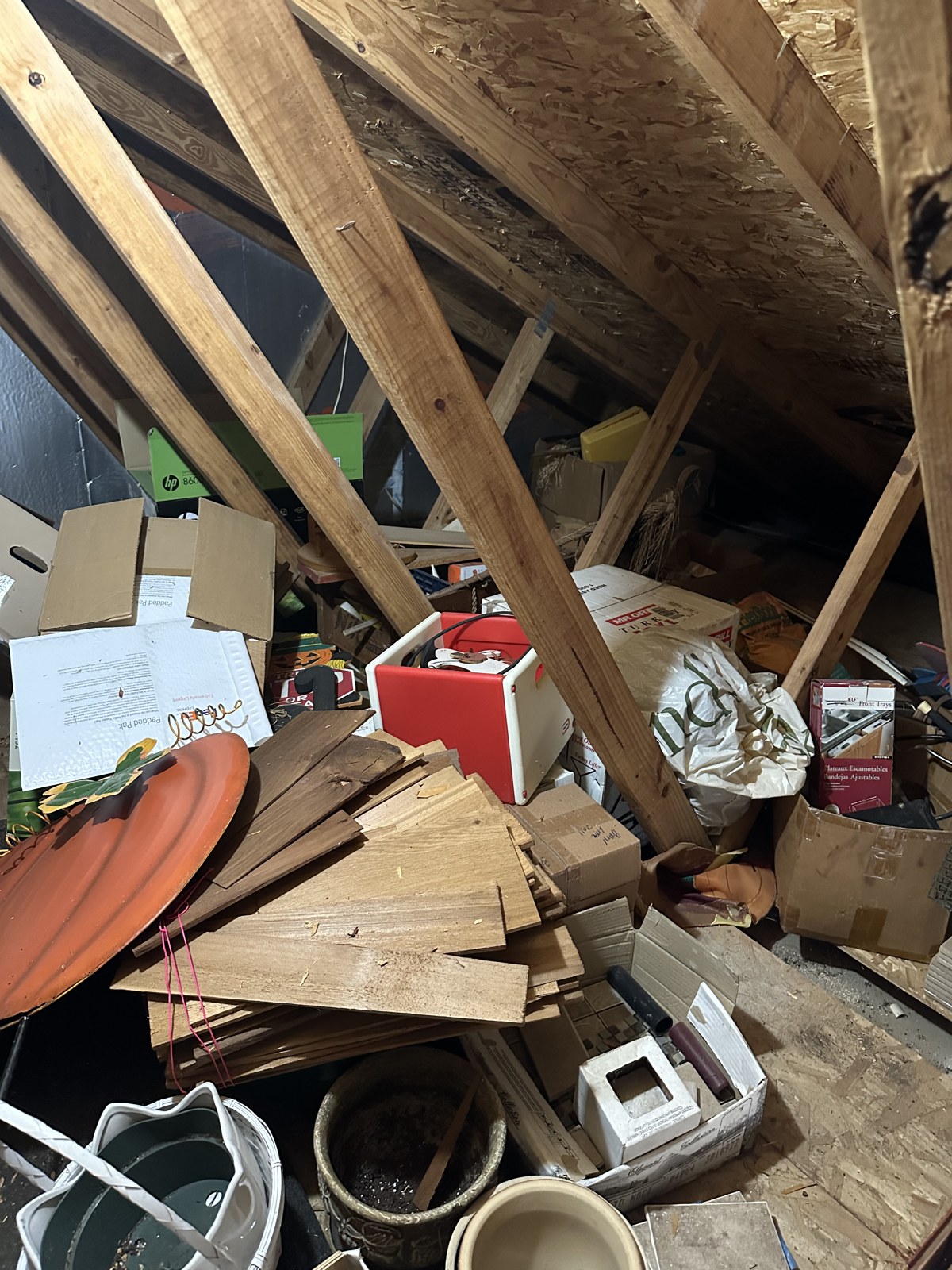 Cluttered attic full of boxes, scrap lumber and old household items