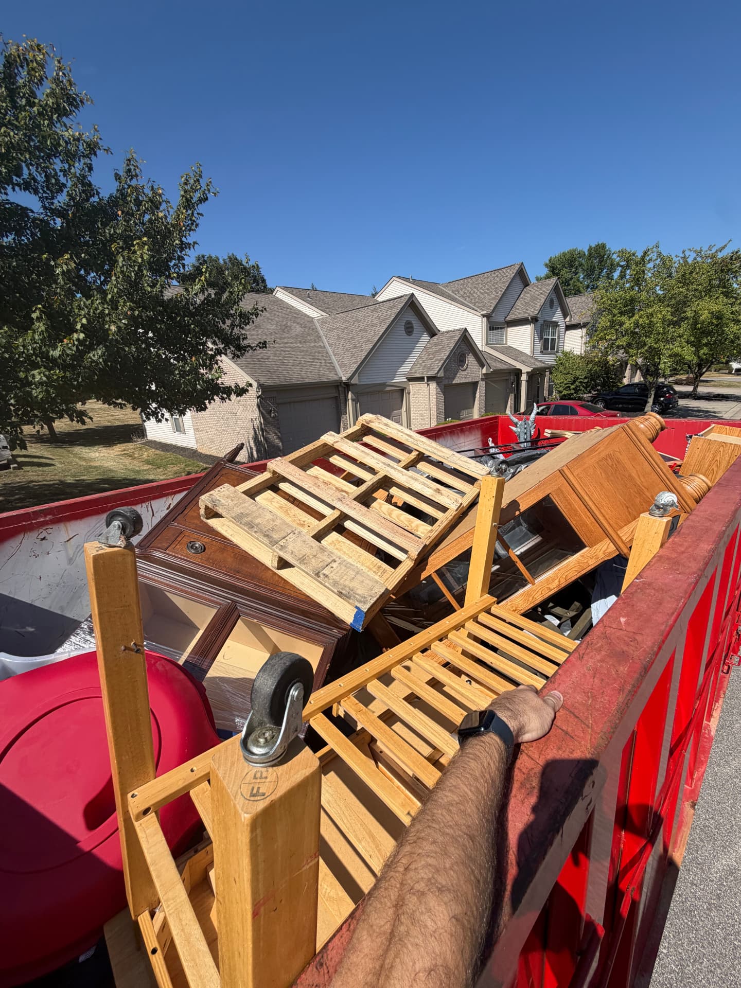 Red Junk Dads trailer loaded with furniture, pallets and a red armchair at a suburban home