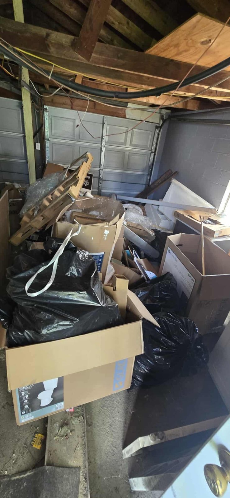Garage packed with cardboard, bagged trash and construction debris before a clean out